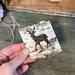 This shows me holding a birch bark gift or accent tag. I have wood burned a deer onto the bark. The bark has a piece of twine tied to it. 
